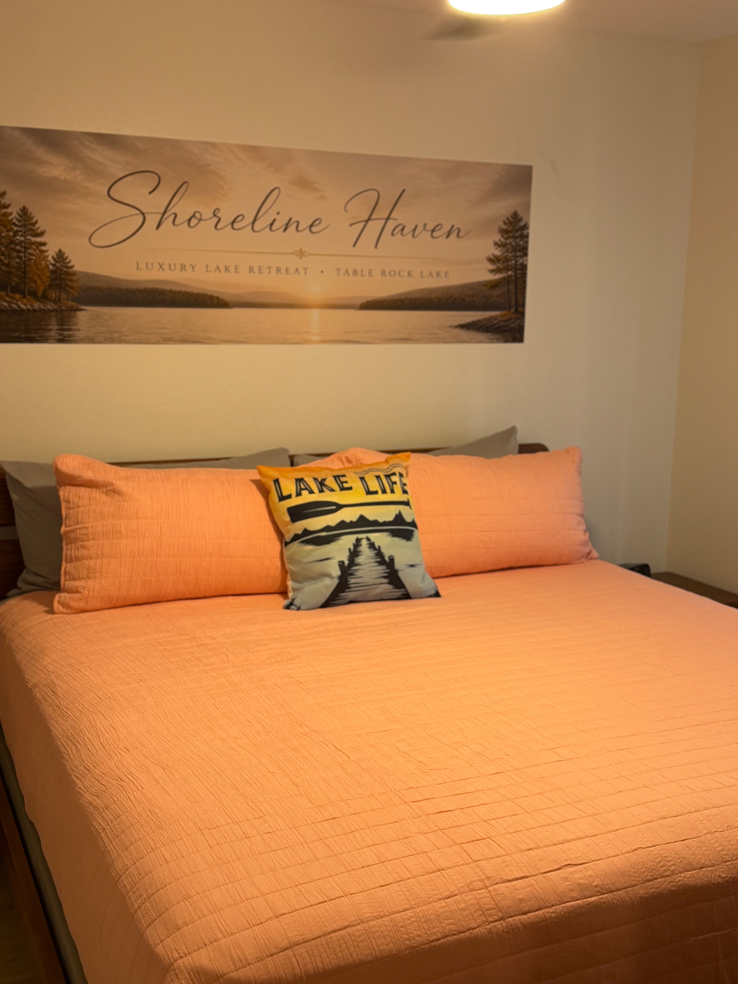 Second bedroom with peach bedding, Lake Life pillow, and Shoreline Haven wall art